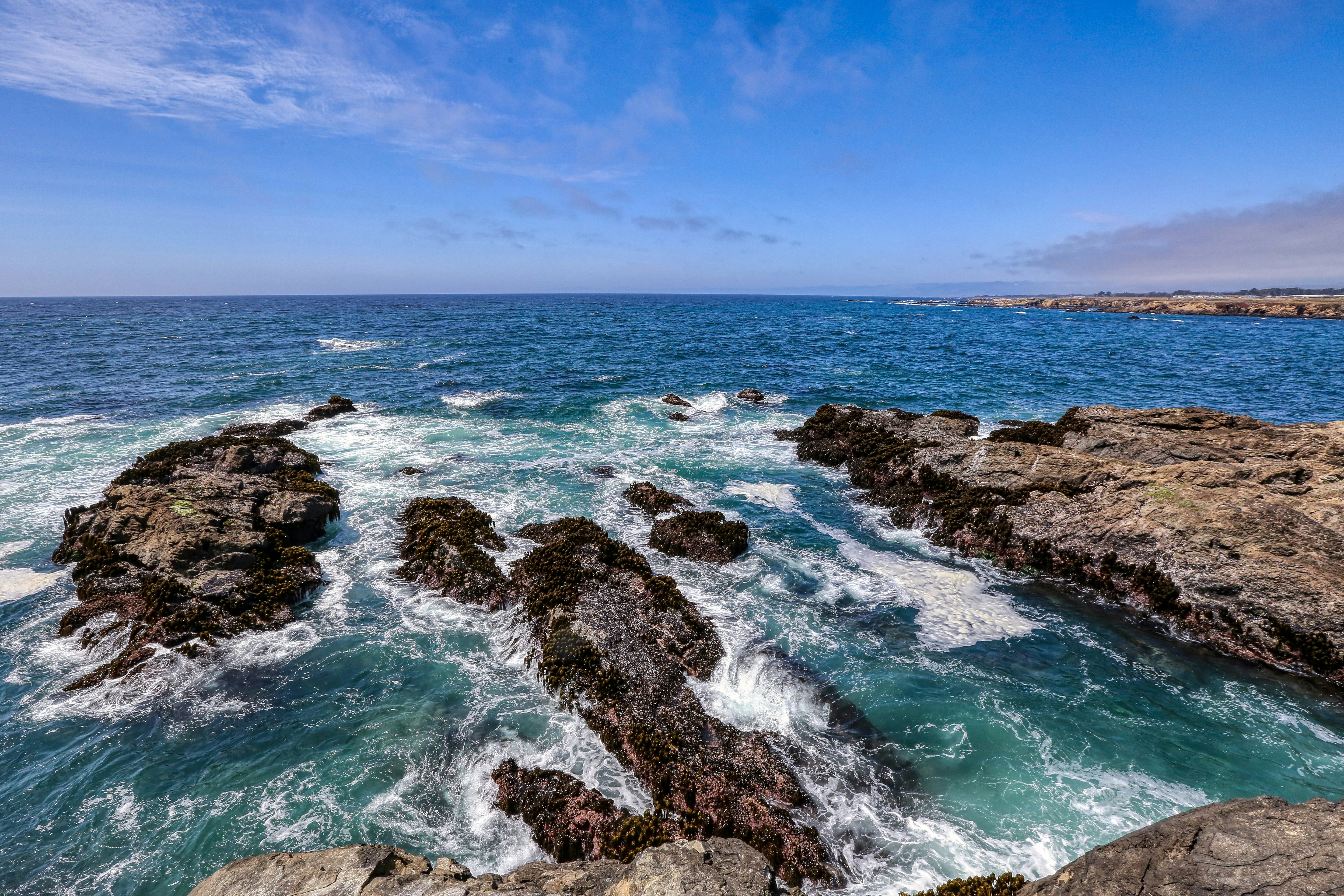 brown rock formation on sea under blue sky during daytime